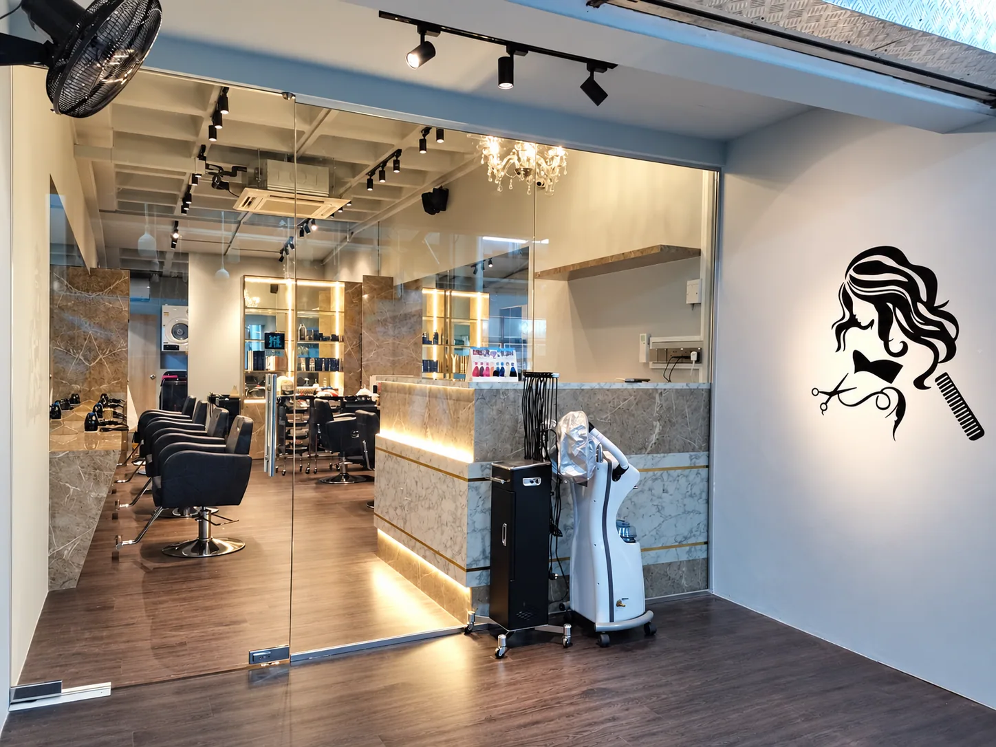 Hair salon entrance with name obscured, illuminated counter and styling stations