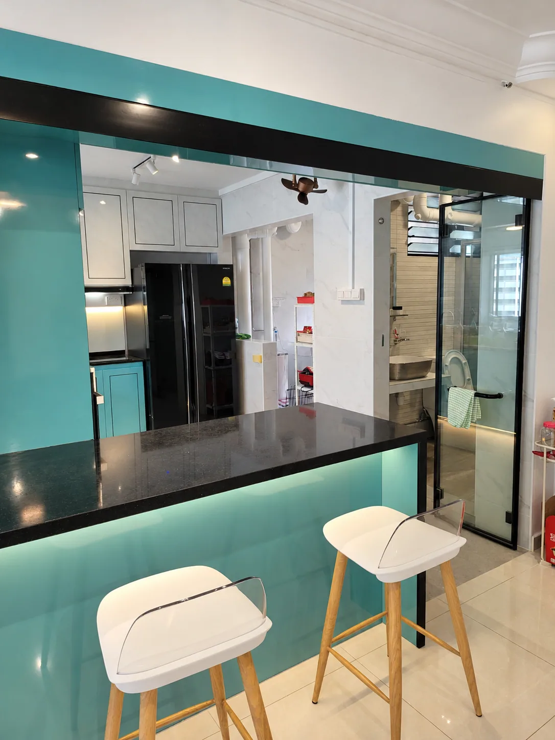 Turquoise kitchen counter with dark worktop and two white stools