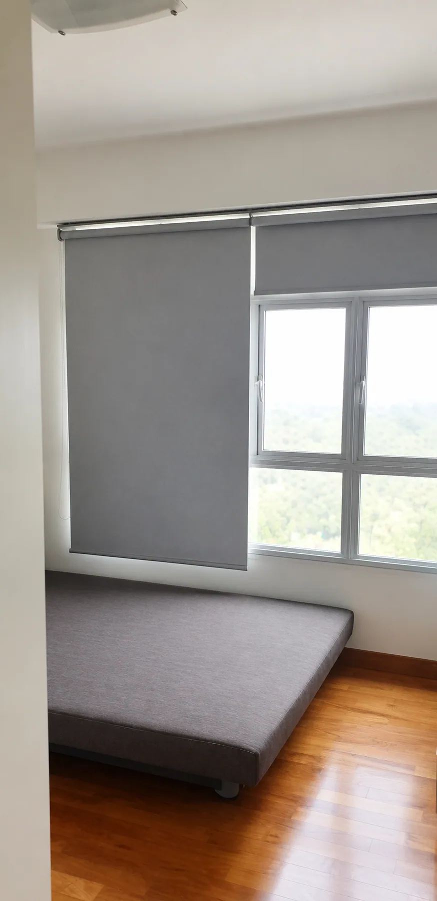 Privacy-edited Yishun HDB bedroom with grey roller blinds and warm wood-look flooring